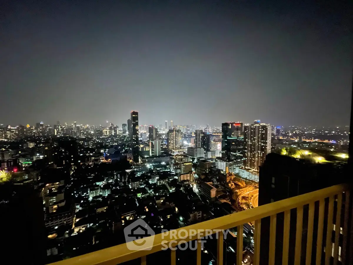 Stunning cityscape view from a high-rise balcony at night, showcasing vibrant urban lights.