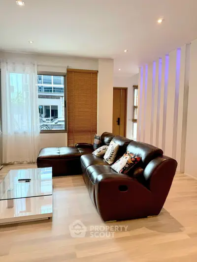 Modern living room with leather sofa and large window in stylish apartment