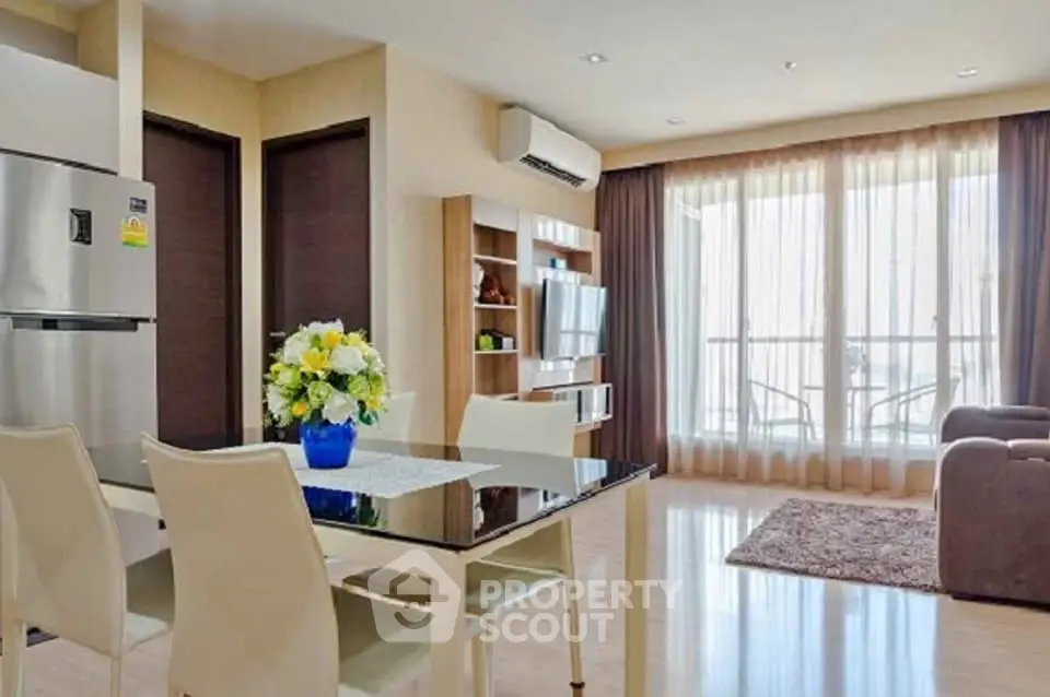 Modern living room with dining area, large windows, and stylish decor in a bright apartment.