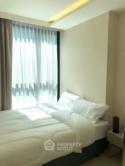 Bright and cozy bedroom with large window and modern decor, perfect for relaxation.