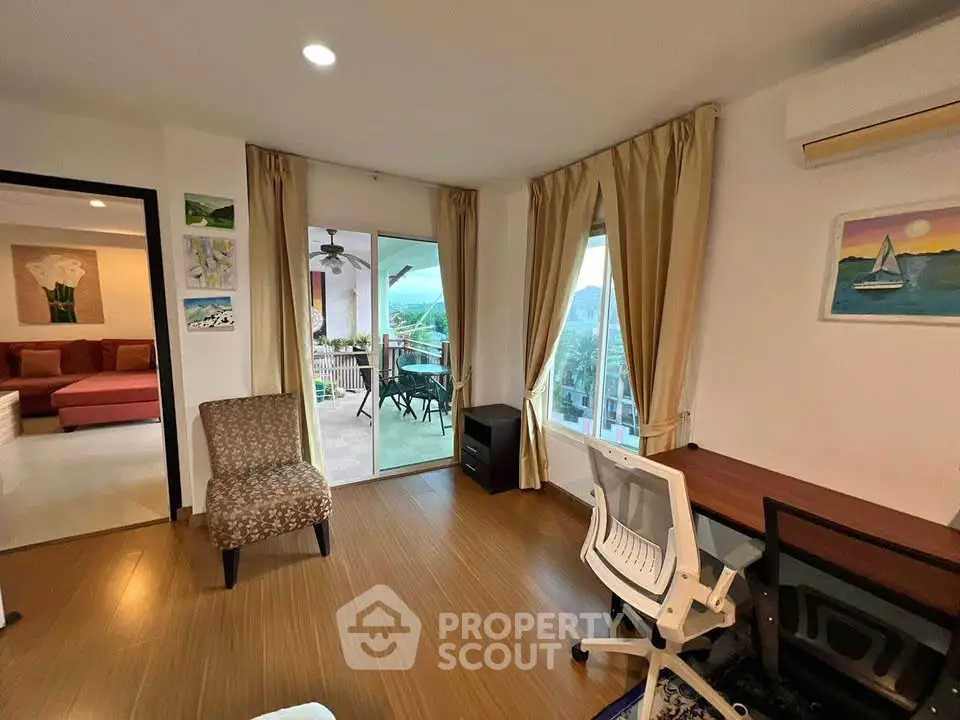 Spacious living room with wooden flooring, elegant curtains, and balcony access offering stunning views.