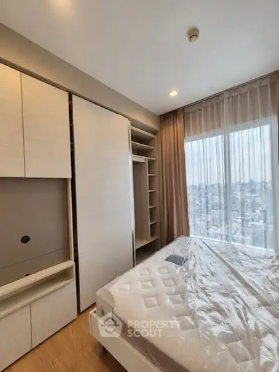 Modern bedroom with large window offering stunning city view and built-in wardrobe.