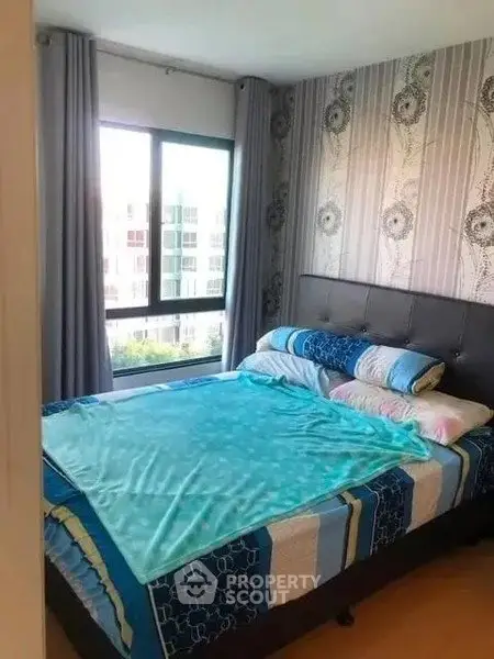 Cozy bedroom with stylish decor and large window offering natural light.