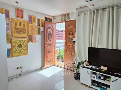 Charming living room with unique wooden doors and vibrant wall art, leading to a cozy outdoor space.
