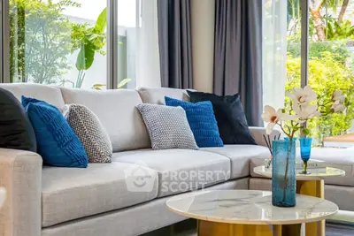 Luxurious living room with elegant sofa and vibrant cushions, featuring large windows and lush garden view.