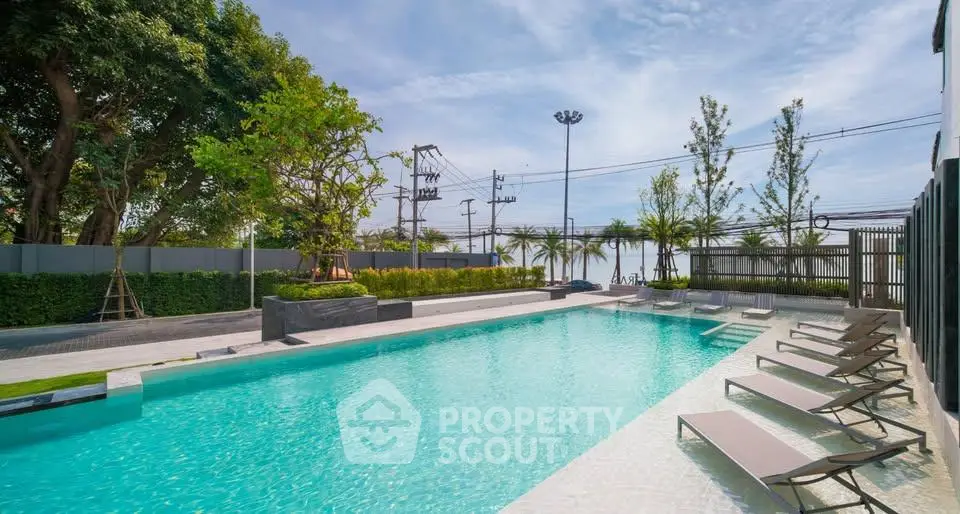 Luxurious outdoor pool area with modern lounge chairs and lush greenery, perfect for relaxation and leisure.