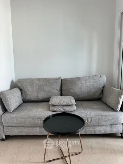 Modern living room with stylish gray sofa and sleek black coffee table on wooden floor.