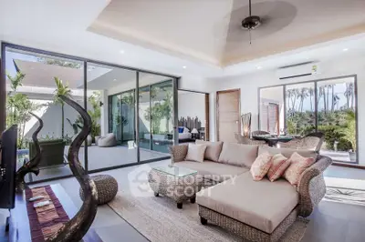 Luxurious modern living room with elegant wicker furniture and expansive glass doors opening to a lush garden view.
