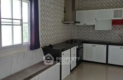 Modern kitchen with stylish backsplash and large window, featuring sleek cabinetry and built-in appliances.