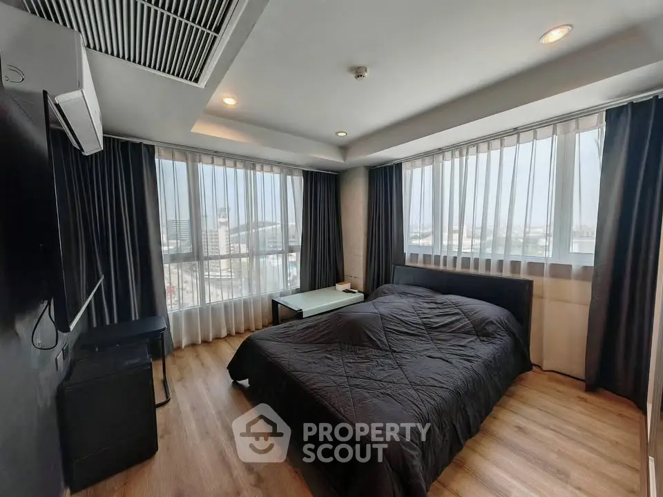 Spacious bedroom with large windows offering stunning city views, modern furnishings, and elegant decor.