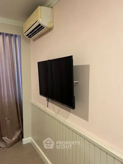 Modern living room with wall-mounted TV and air conditioning unit, featuring elegant curtains and wainscoting.