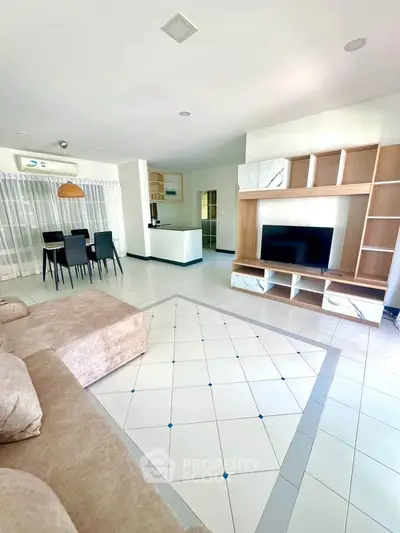 Spacious open-plan living room with modern entertainment unit and cozy seating area.