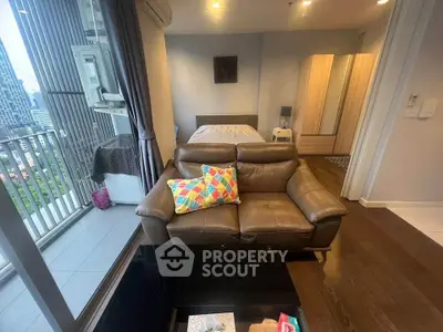 Modern studio apartment with balcony and city view, featuring cozy leather sofa and stylish decor.