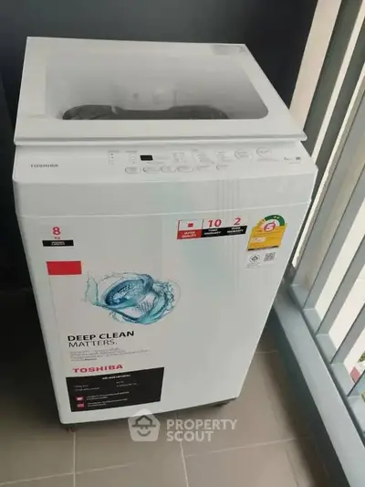 Modern Toshiba washing machine on a balcony with sleek railing design.