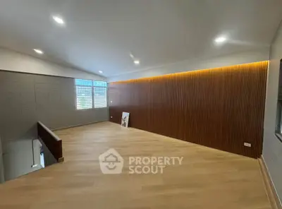 Spacious modern living room with wooden flooring and accent wall, ideal for contemporary living.