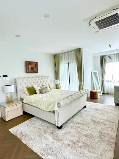 Luxurious bedroom with elegant decor and large windows offering natural light.