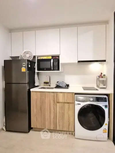 Modern kitchen with sleek appliances and compact design, featuring a washing machine and microwave.