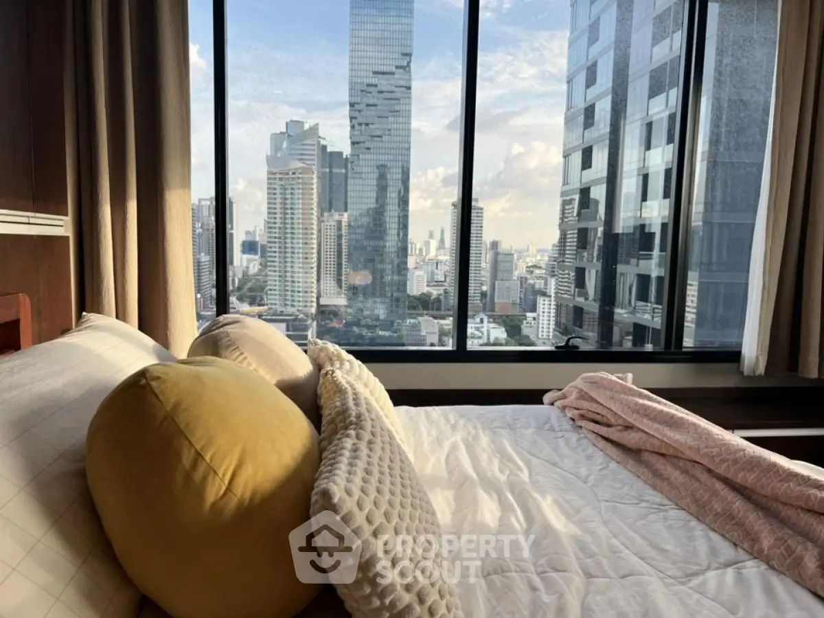 Luxurious bedroom with stunning city view from large window in high-rise apartment.