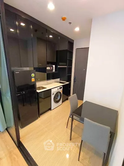 Modern kitchen with sleek black cabinets, built-in appliances, and cozy dining area.
