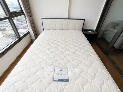 Spacious bedroom with large windows and a comfortable pocket coil mattress, offering a stunning city view.