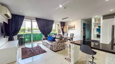 Spacious modern living room with open kitchen and balcony view in urban apartment.