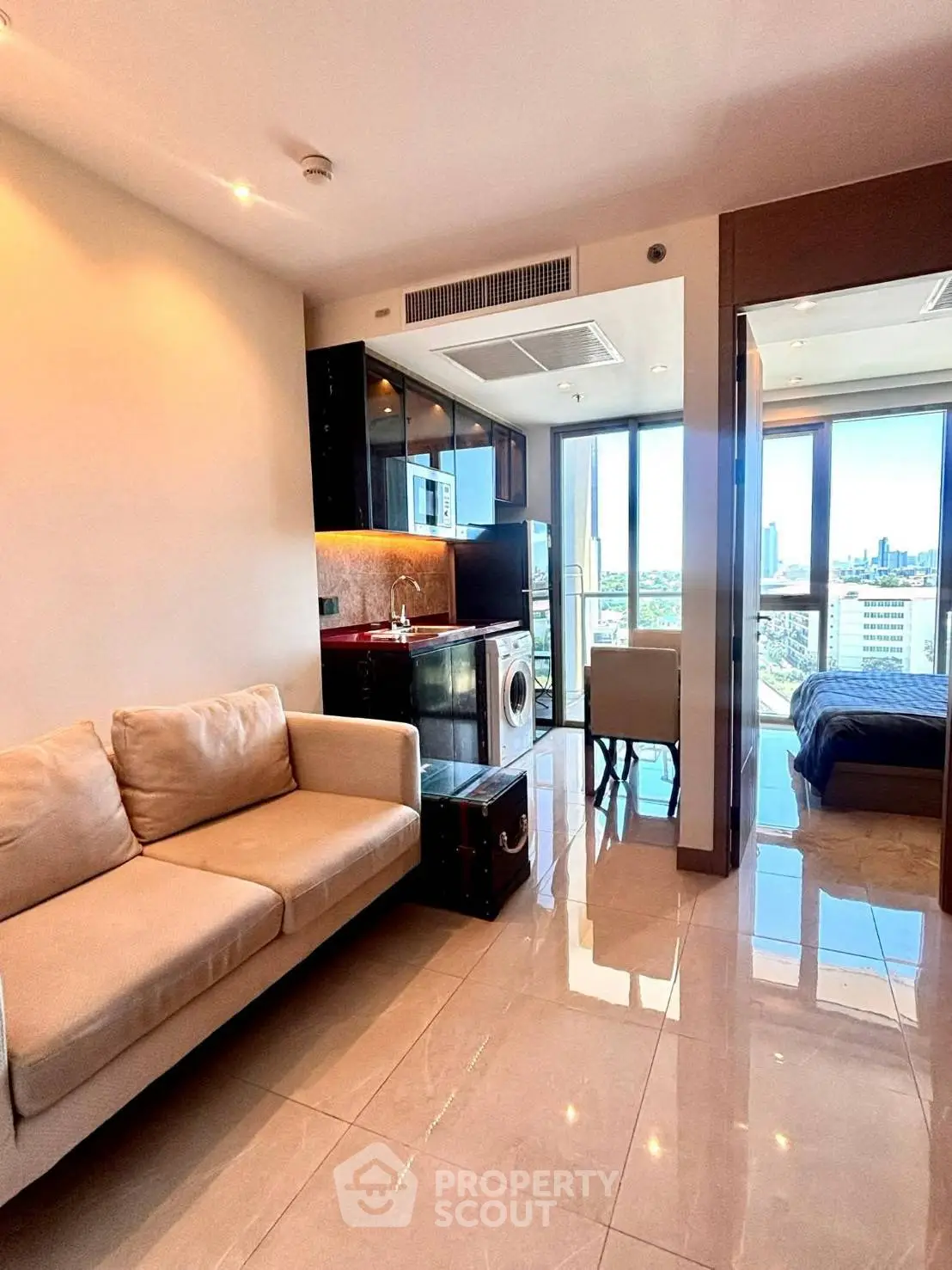 Modern apartment interior with open layout, featuring a cozy living area and kitchen with city views.