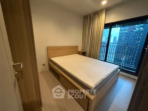 Modern bedroom with city view and large window in high-rise apartment.