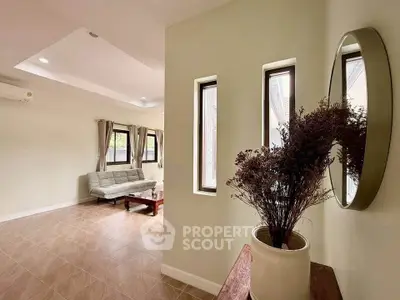 Spacious living room with modern decor and natural light, featuring a cozy sofa and elegant plant arrangement.