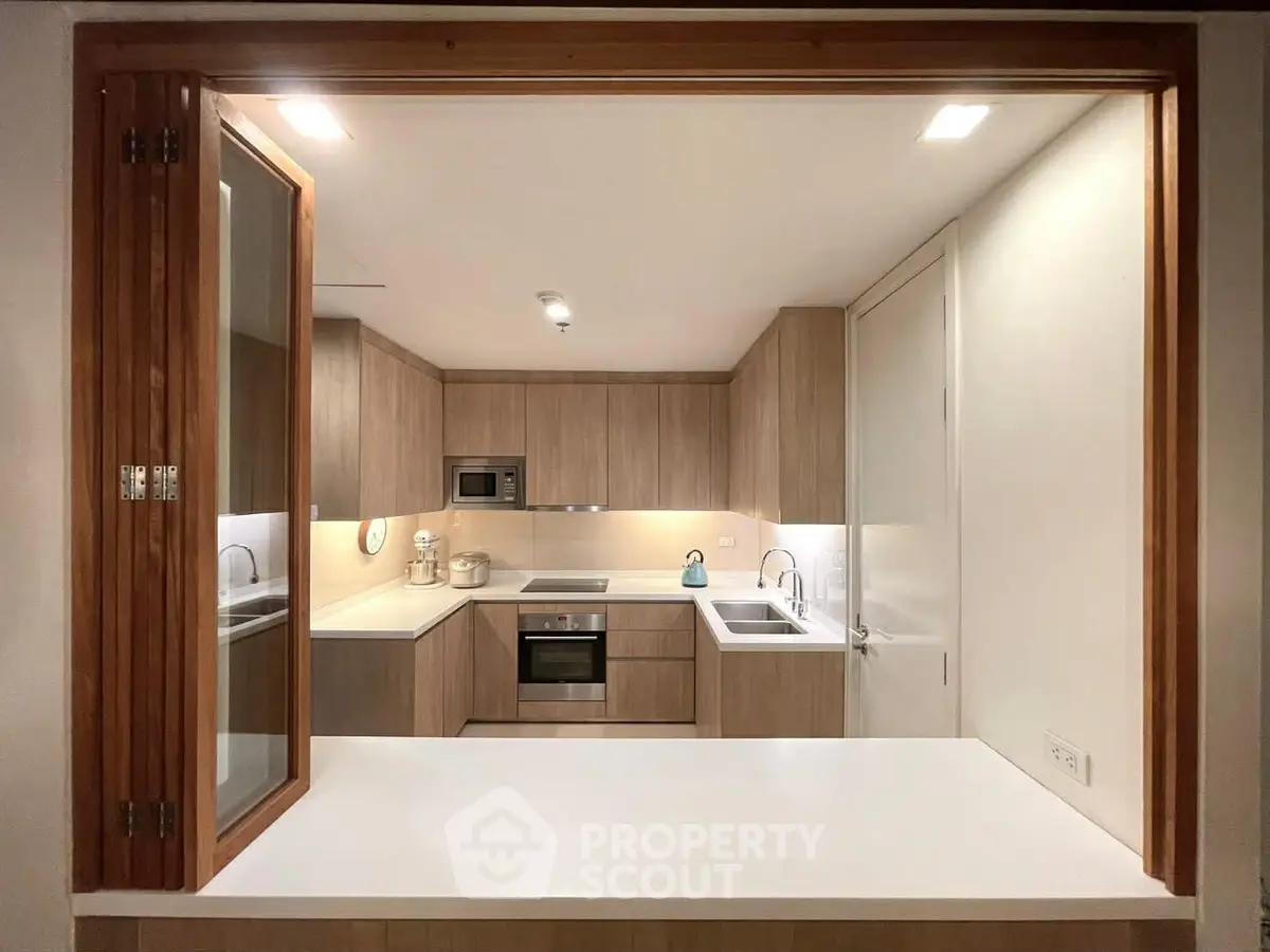 Modern kitchen with sleek wooden cabinetry and built-in appliances, featuring a convenient open layout.