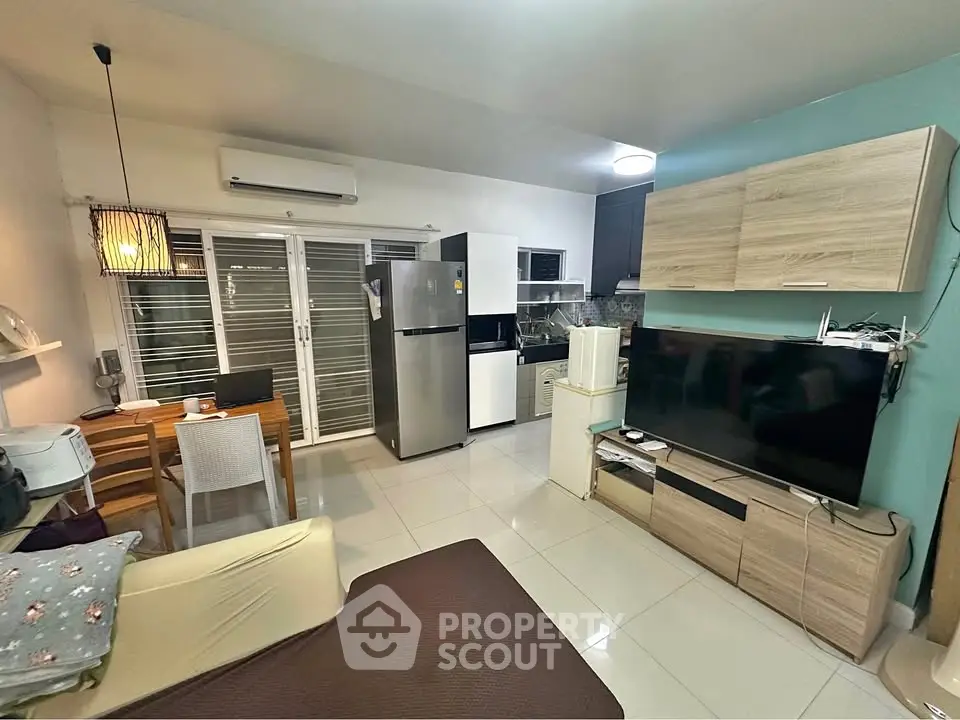 Modern living room with open kitchen, featuring sleek appliances and stylish furniture.
