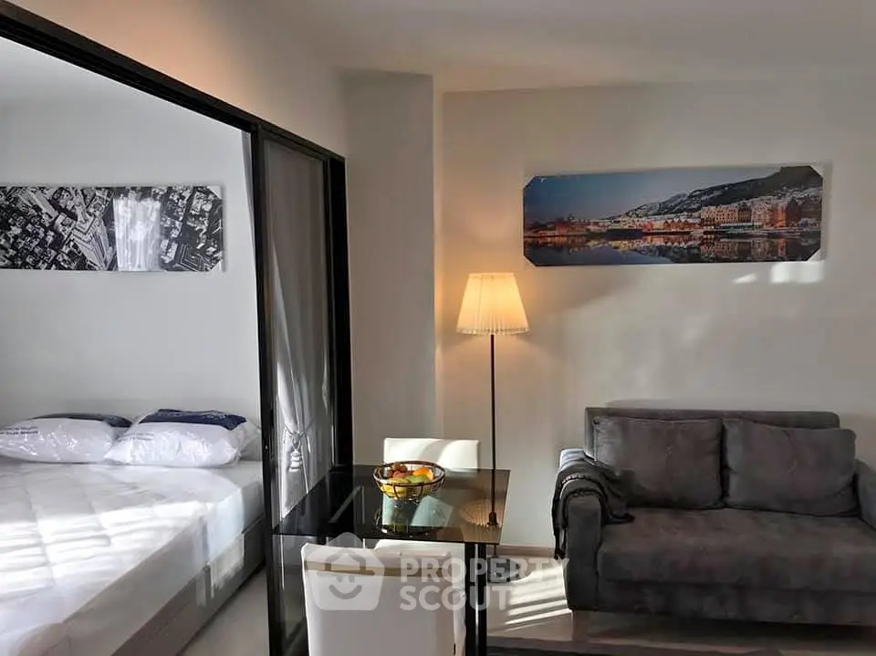 Modern living room with cozy sofa and adjacent bedroom in open layout apartment.