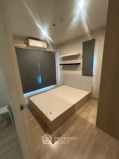 Modern bedroom with minimalist design and natural light, featuring sleek furniture and wooden flooring.