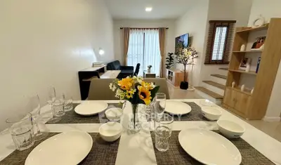 Modern dining area with elegant table setting and cozy living room view.