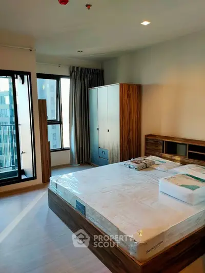 Modern bedroom with large window and stylish wooden furniture in a high-rise apartment.