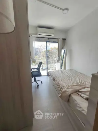 Cozy bedroom with natural light and balcony access, perfect for serene living.