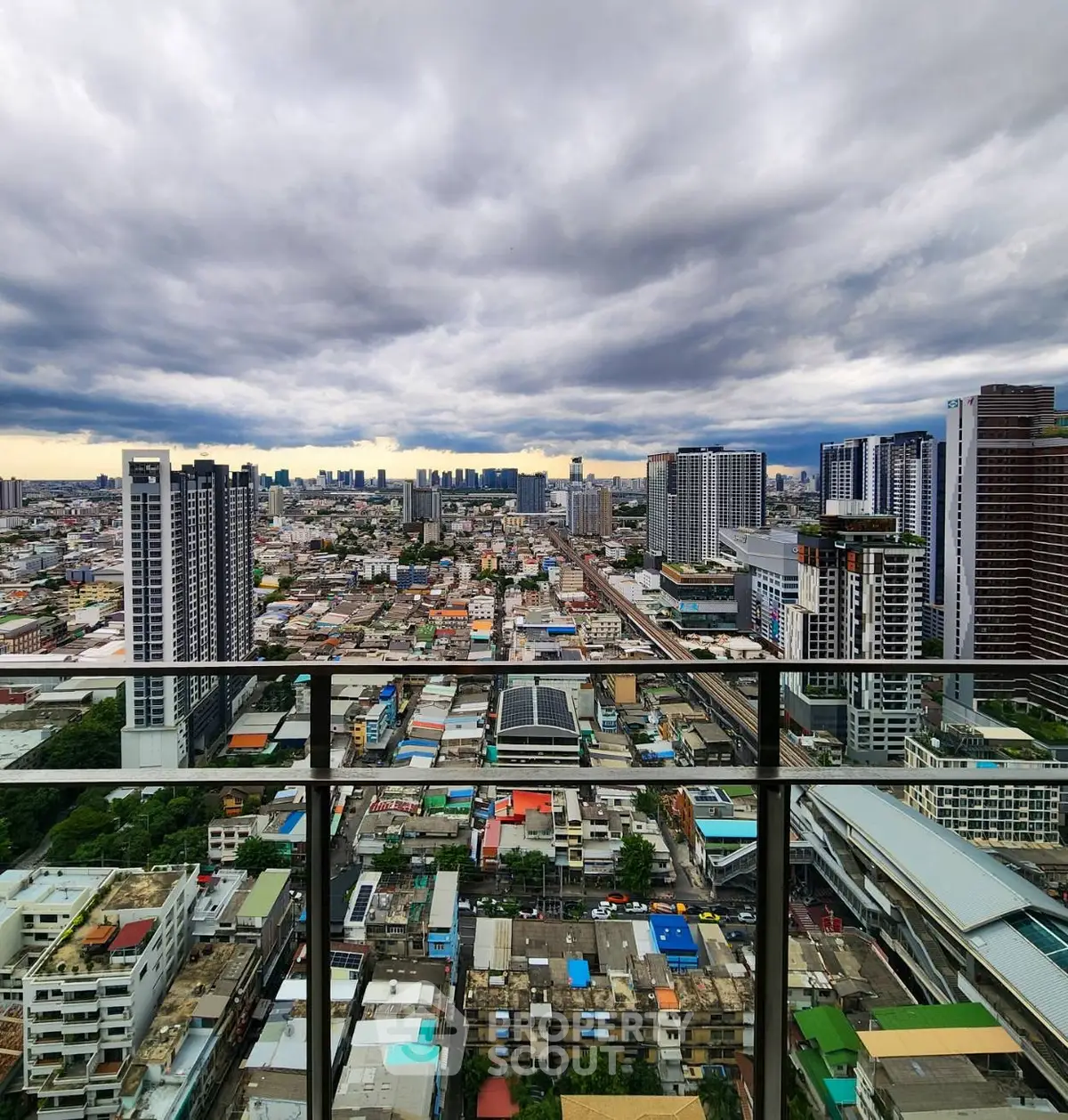 Stunning cityscape view from a high-rise balcony showcasing urban skyline and dramatic clouds.