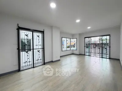 Spacious living room with large windows and elegant metal grills, perfect for natural light and security.