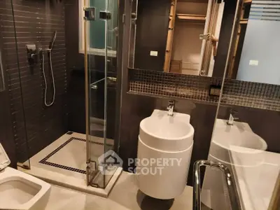 Modern bathroom with sleek fixtures and glass shower enclosure in contemporary apartment.
