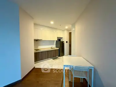 Modern kitchen with sleek cabinetry and dining area in open layout apartment.