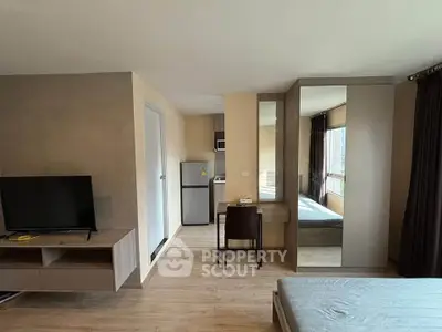 Modern studio apartment with sleek furniture and natural light, featuring a compact kitchen and cozy living area.