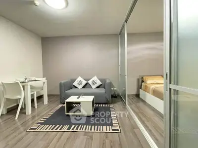 Modern living room with cozy sofa and dining area, featuring sliding glass doors to bedroom.