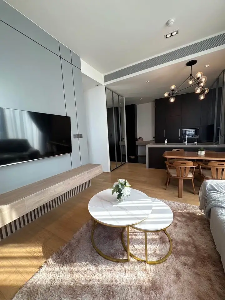 Modern living room with open kitchen, stylish furniture, and elegant lighting in a contemporary apartment.