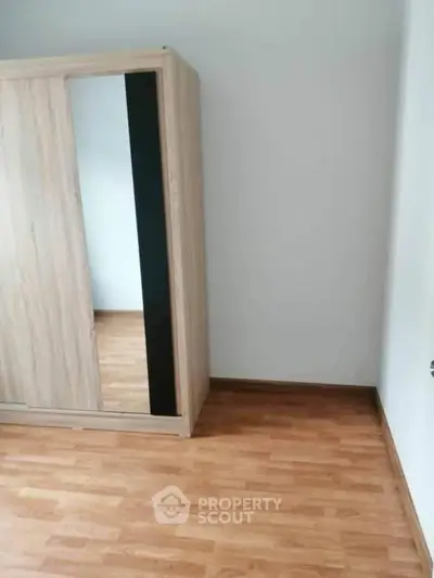 Spacious bedroom with wooden wardrobe and laminate flooring