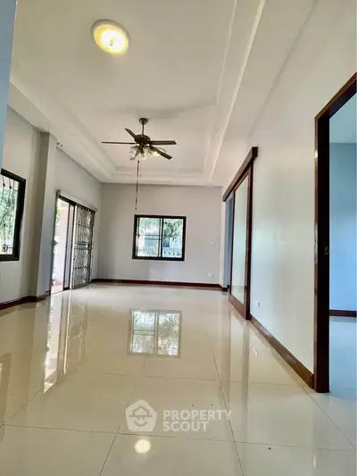 Spacious living room with glossy tiled floors and ceiling fan, ideal for modern living.