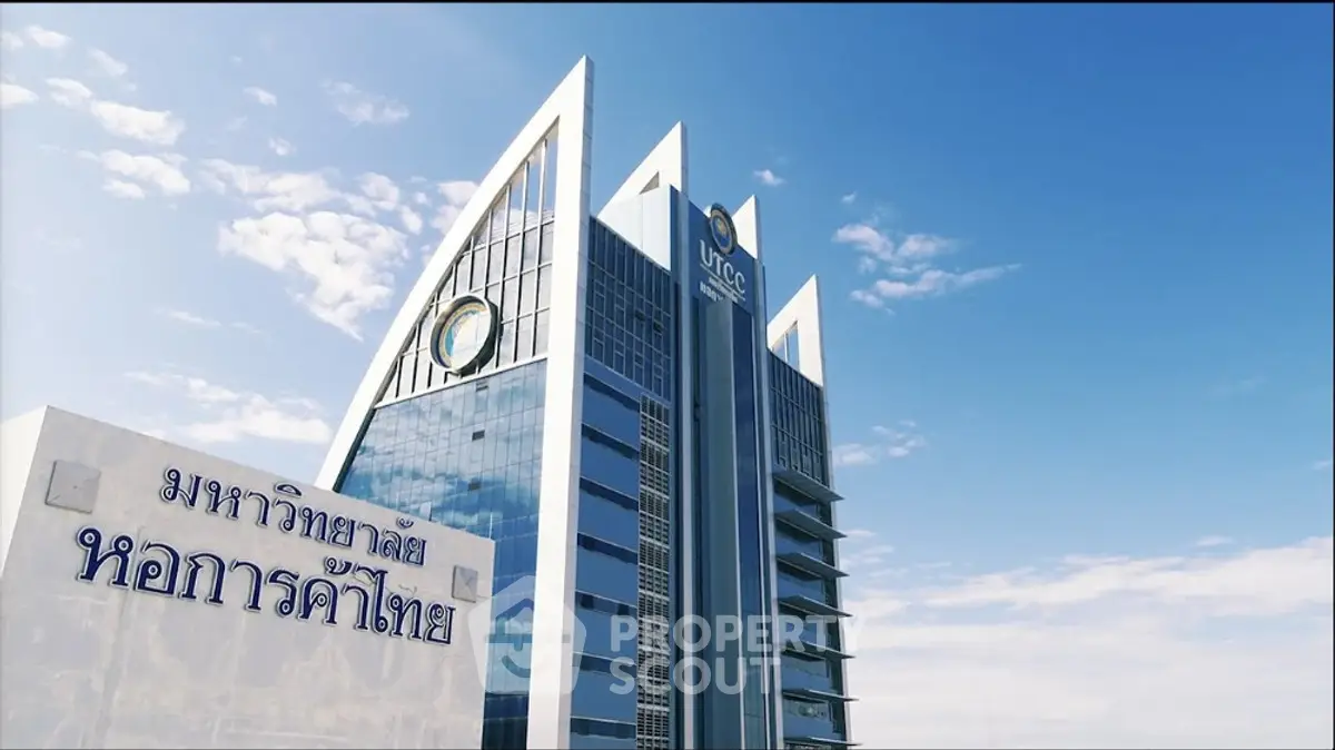 Modern architectural building with sleek glass facade and unique triangular roof design under a clear blue sky.