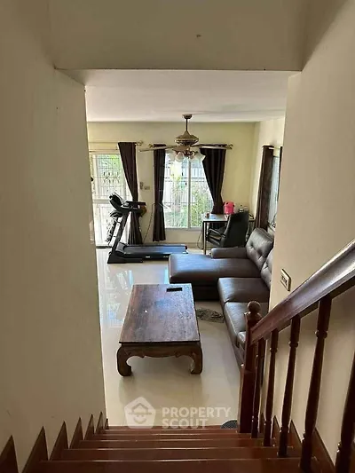 Spacious living room with modern furniture and treadmill, perfect for relaxation and fitness.