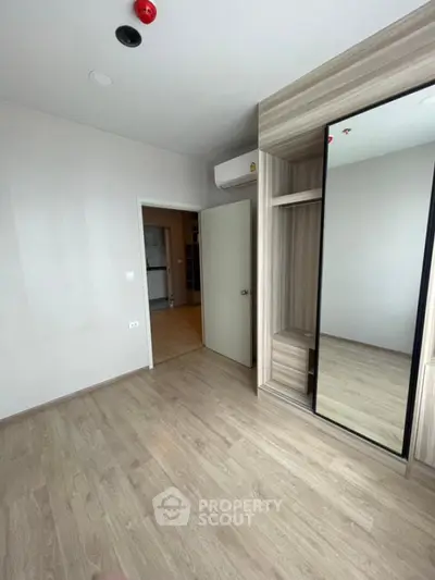Spacious modern bedroom with wooden flooring and mirrored wardrobe