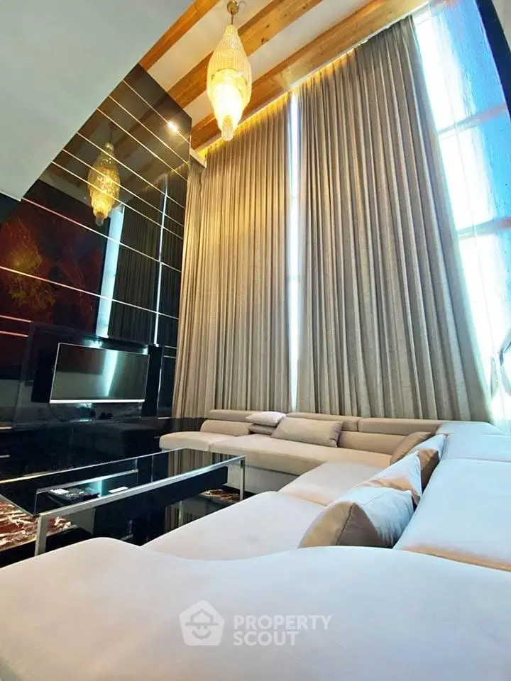 Luxurious living room with high ceilings, elegant chandelier, and plush sectional sofa.