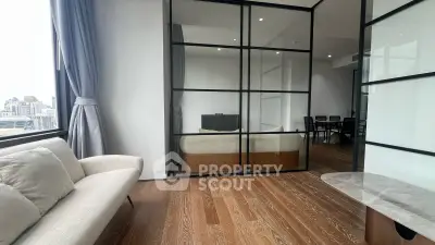 Modern living room with glass partition and city view, featuring sleek furniture and wooden flooring.