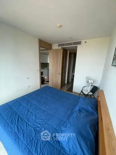 Modern bedroom with blue bedding and wooden accents, featuring a sleek design and ample natural light.